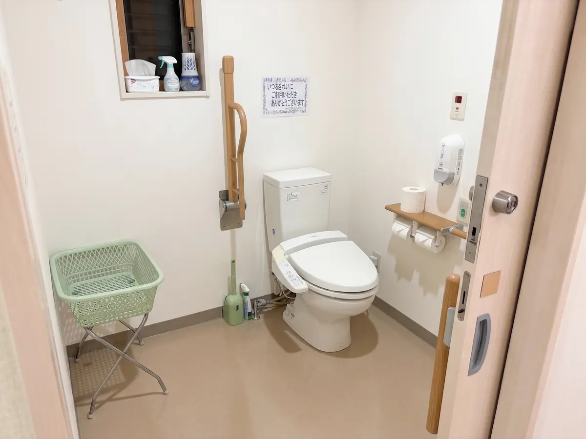 つつみ脳神経外科クリニックのお手洗いの個室内部。壁に縦型の手すりと呼出ボタンが備え付けられている。